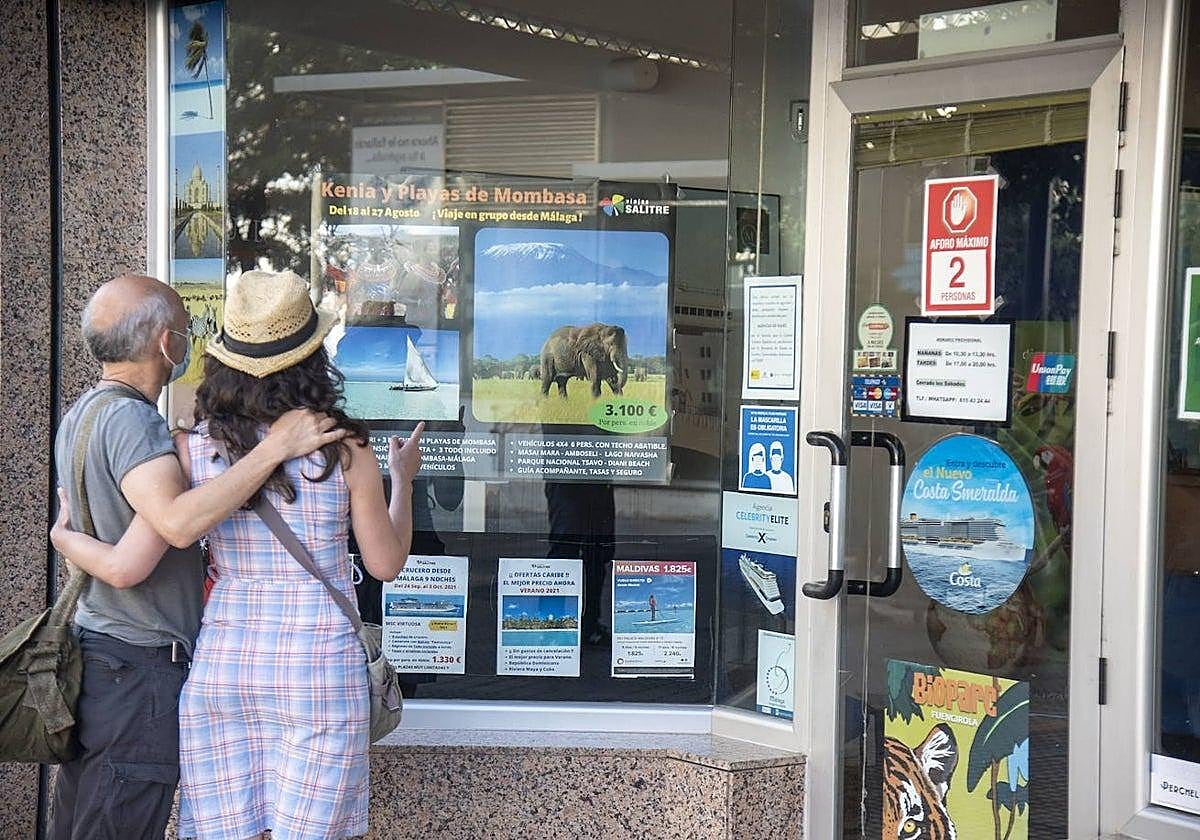 Una pareja contempla las ofertas en el escaparate de una agencia de viajes.