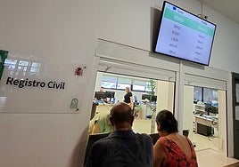 Dos usuarios esperan a ser atendidos en el Registro Civil.
