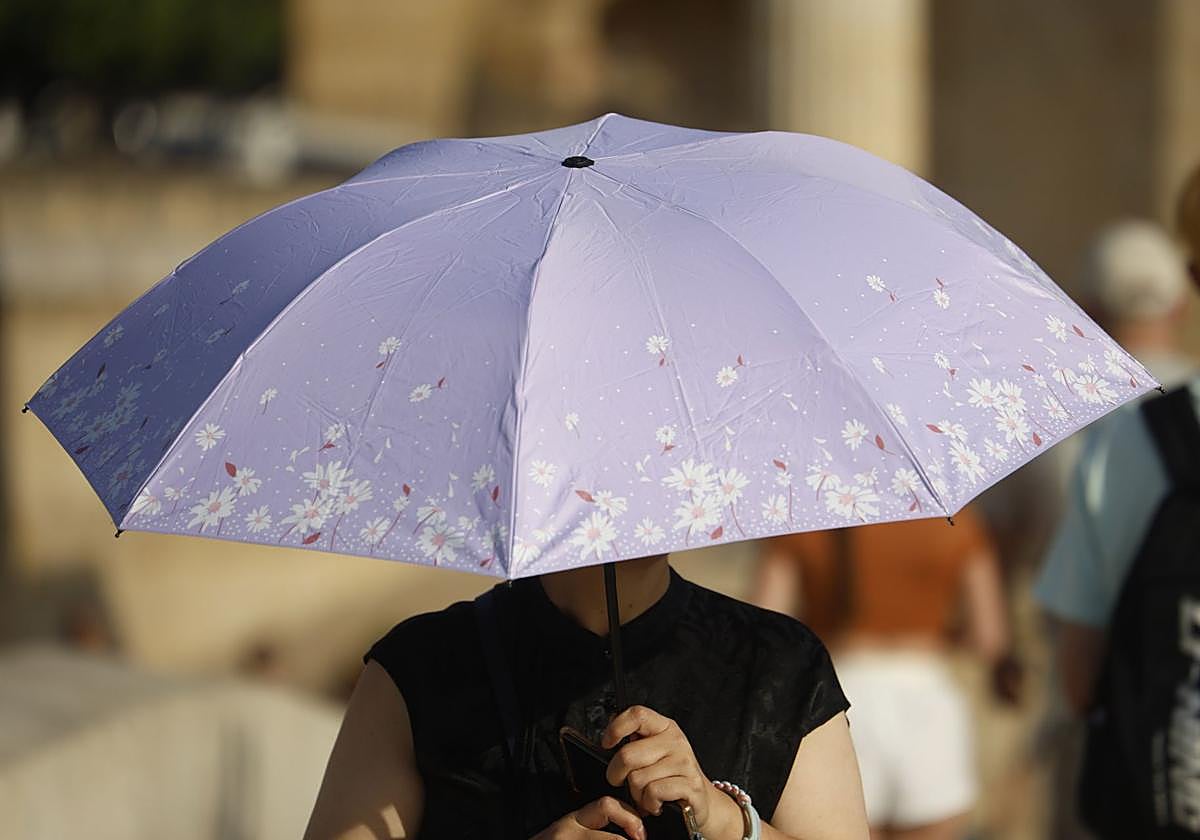 Una meujer se protege del sol con un paraguas.