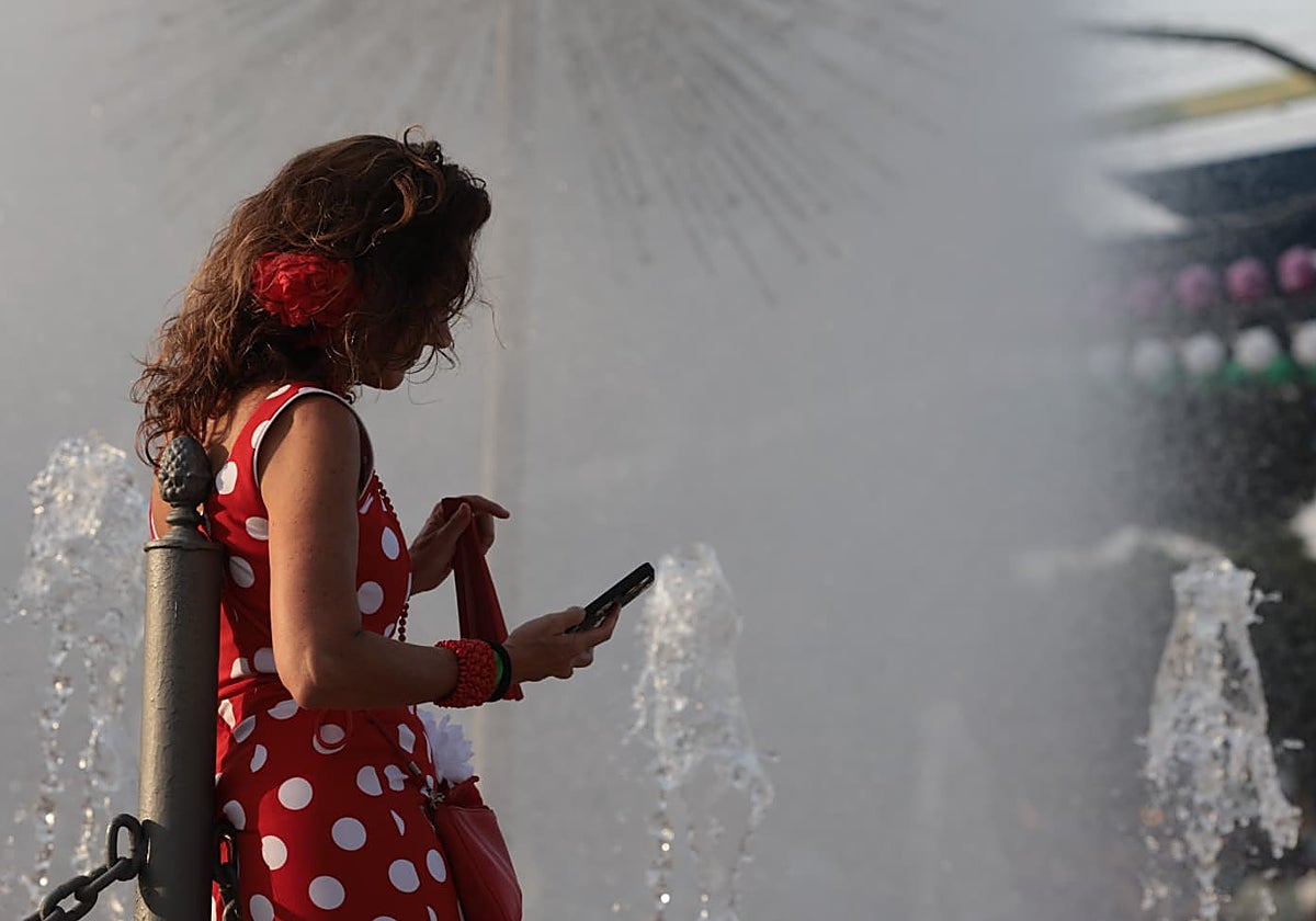 Una asistente al real de la feria busca el frescor de las fuentes para descansar.
