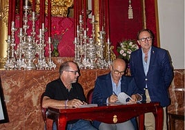 Salvador Aguilar, firmando, ante la presencia de Manuel Mendoza y Javier Martín, hermano mayor del Rocío.