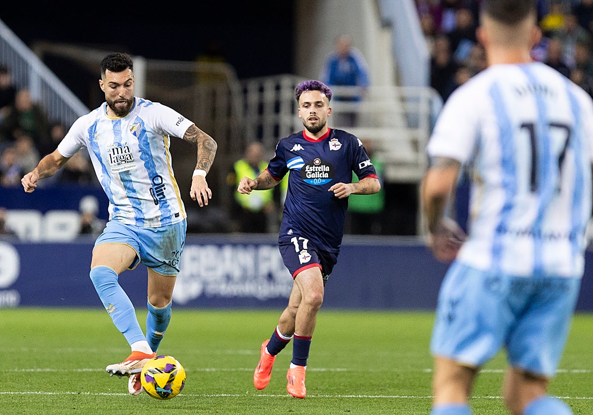 Álex Pastor da un pase, con David Mella del Deportivo a su lado, en el último enfrentamiento entre ambos equipos en La Rosaleda.