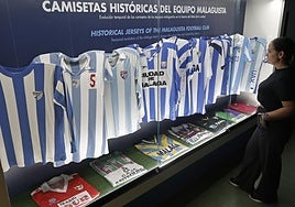 Una guía del museo observa la vitrina de camisetas históricas.