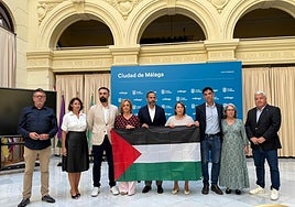 Los concejales del grupo socialista, con su portavoz Dani Pérez, con la bandera palestina, en la rueda de prensa en el patio de Banderas del Ayuntamiento de Málaga.