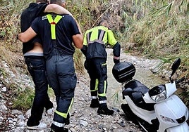 Los efectivos del Consorcio Provincial de Bomberos, en el rescate del joven, junto a la motocicleta.