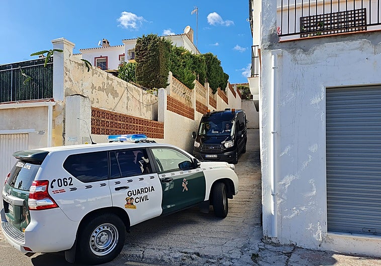 Una patrulla de la Guardia Civil y el furgón funerario, en una de las entradas de la urbanización.