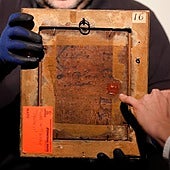 El comisario señala el sello lacrado de la familia real británica en el reverso del óleo de Felipe II.