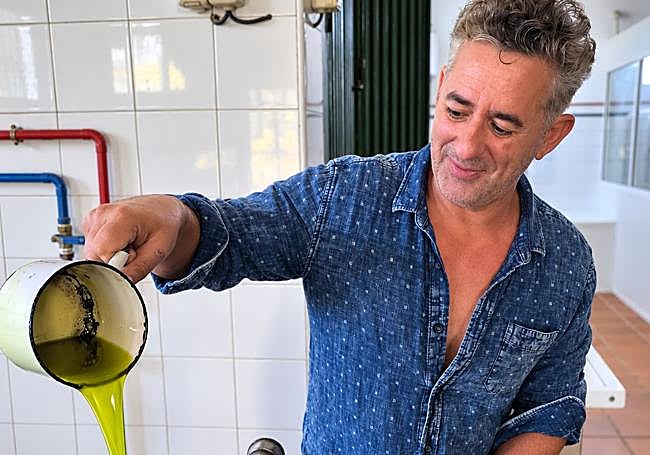 Rafael Mota, del Molino de La Paca, muestra el primer zumo de aceitunas obtenido.