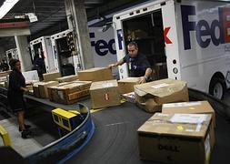 Trabajdores de Fedex clasifican paquetes en una central en Florida. / Efe