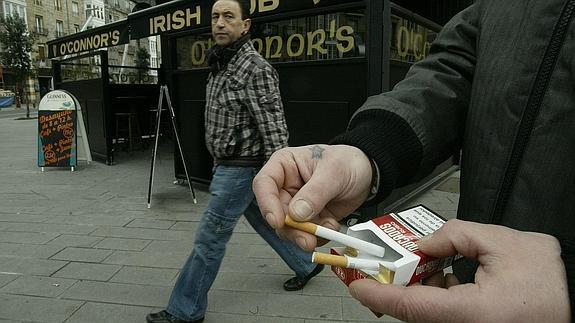 Un hombre saca un cigarro de una cajetilla 