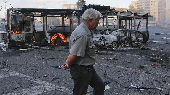 Un hombre camina junto a varios vehículos calcinados en Donetsk. 