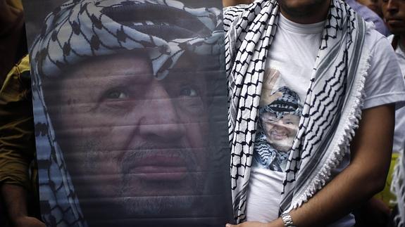 Un palestino muestra una imagen de Arafat.