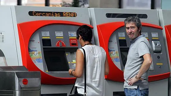 Dos pasajeros sacan un billete en una estación de Renfe 