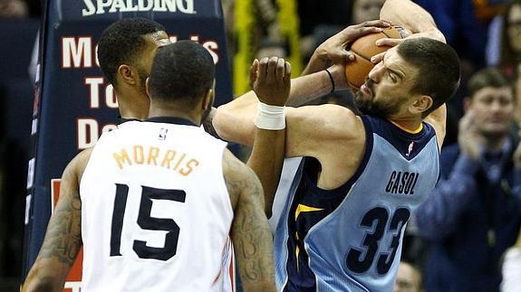 Los jugadores de Suns Markieff Morris (i) y Marcus Morris (c) disputan el balón con Marc Gasol. 