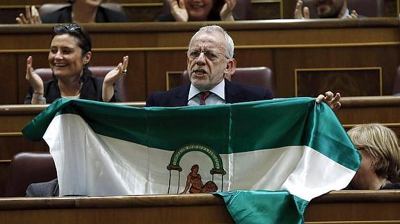 El diputado socialista Manuel Pezzi muestra una bandera de Andalucía. 