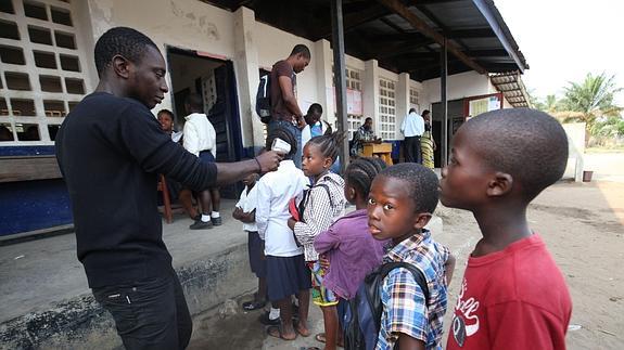 Un inspector sanitario, junto a un grupo de estudiantes a las afueras de Monrovia (Liberia).