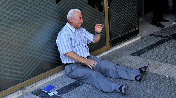 Un pensionista llora desconsolado a la puerta de un banco. 