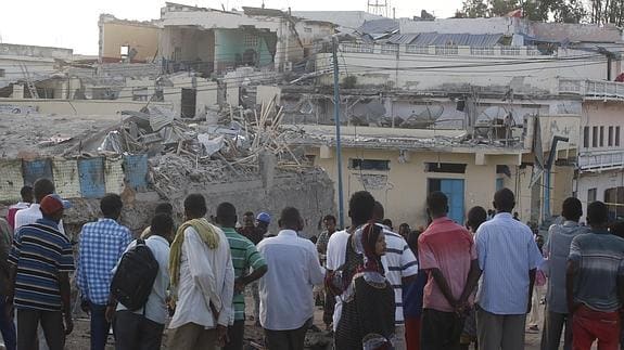 Un grupo de personas observa la escena de un atentado terrorista en Somalia.