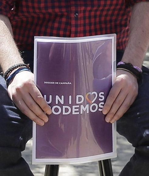 Pablo Iglesias sostiene el programa electoral con la nueva imagen de la coalición Podemos-Izquierda Unida.