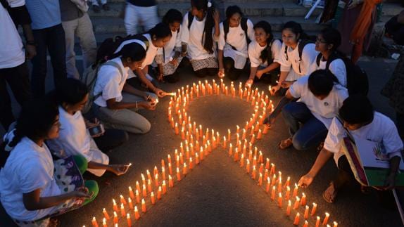 Varios jóvenes indios encienden velas para formar un lazo contra el cáncer.