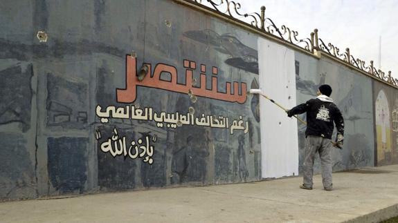Un voluntario tapa pintadas a favor del Daesh en un muro de Mosul.