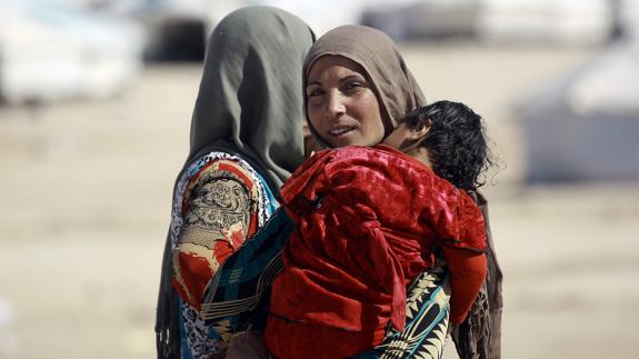 Una mujer con un niño en brazos en un campo de refugiados sirio tras abandonar Mosul. 