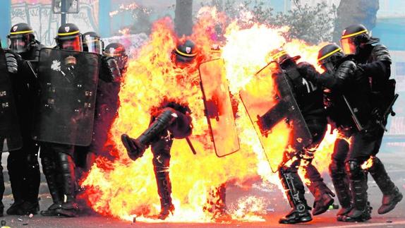 Policía envuelto en llamas durante los disturbios de París.