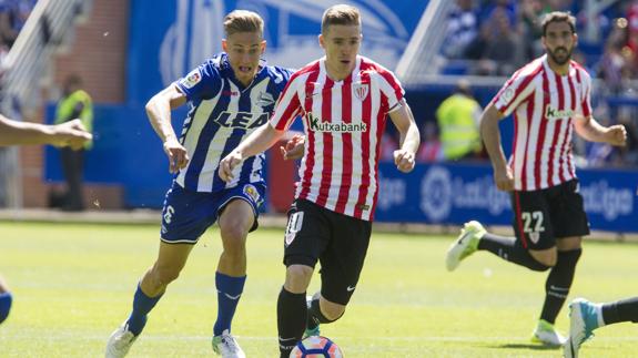 Muniain conduce el balón, perseguido por Marcos Llorente. 