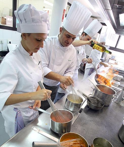 Unos alumnos de cocina preparan unas salsas bajo la supervisión del profesor.