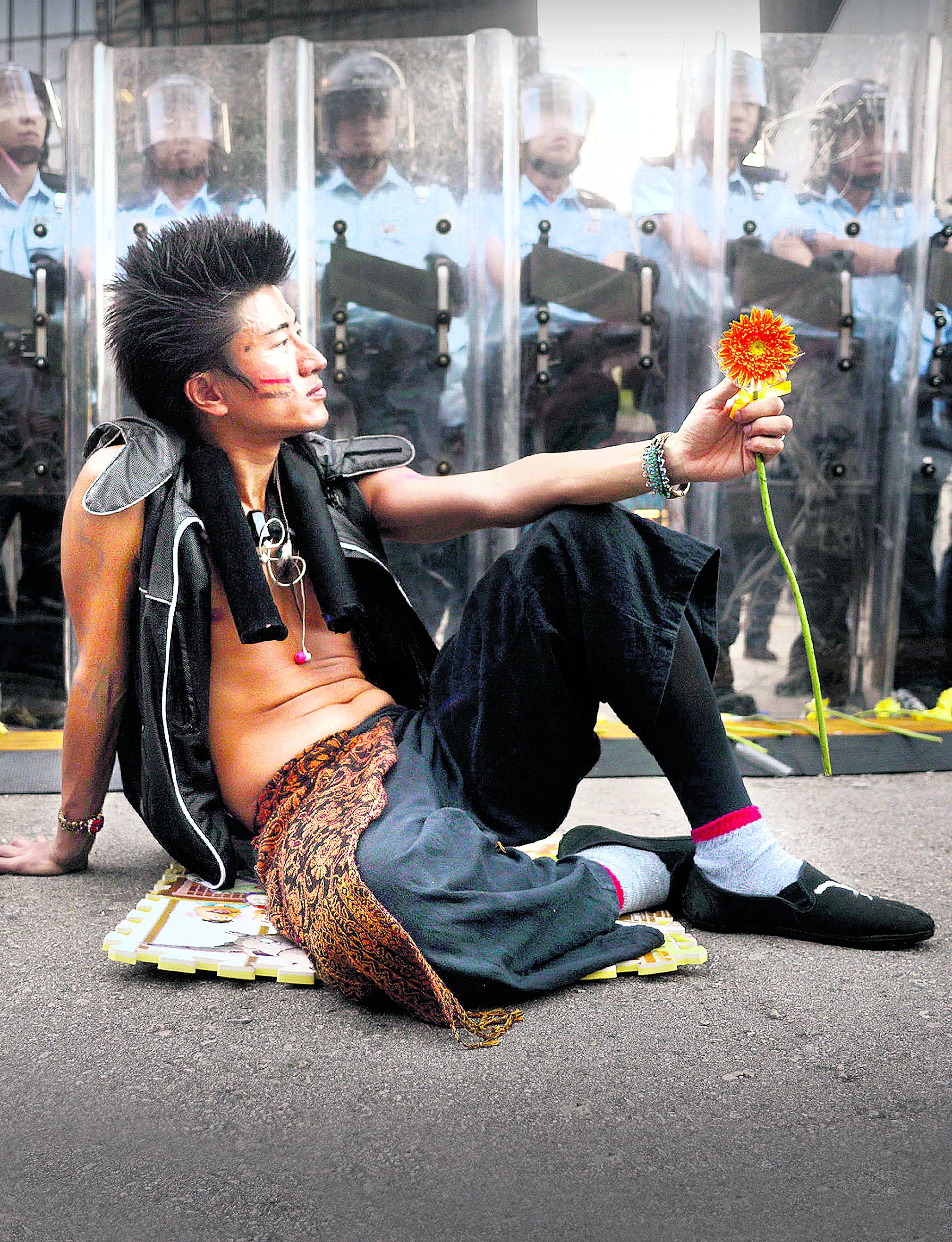 Un estudiantereta a los antidisturbios con una flor en la mano. 