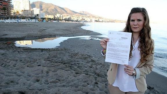 Nuria posa con la denuncia en la playa de Fuengirola donde ocurrieron los hechos. 