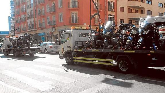 Dos grúas cargadas de motos circulan por calle Cuarteles ayer pasadas las cinco de la tarde.