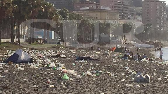 Imagen de la playa de la Malagueta esta mañana con suciedad y una tienda de campaña.
