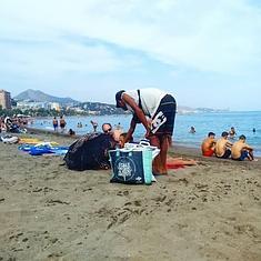 Un hombre recorre la playa ofreciendo sus productos a los bañistas.