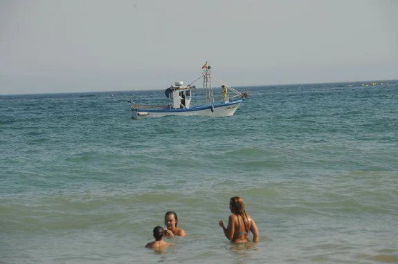 Barco pescando medusas en una playa de Marbella este pasado verano.