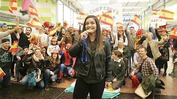 María Torres muerde la medalla de oro lograda en Chipre delante de sus amigos y familiares ayer en la estación María Zambrano. 