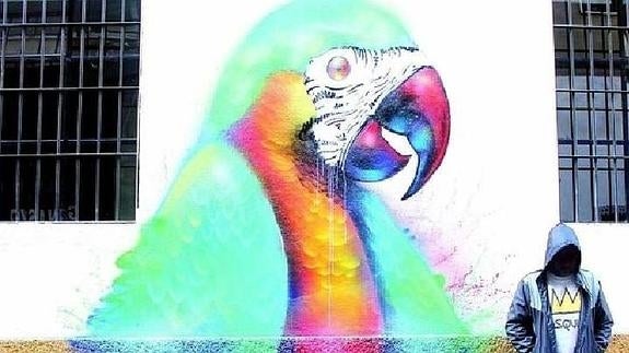 Ddarko oculta su rostro junto a una de sus obras