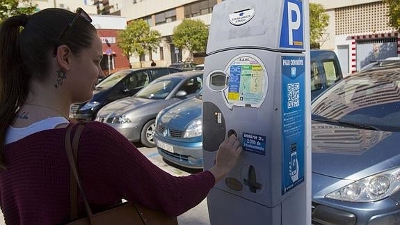 Una usuario inserta una moneda en el parquímetro tras estacionar su vehículo en la capital.