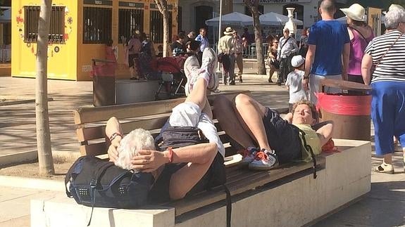 Una pareja de turistas descansa en un banco de la plaza de La Merced. 