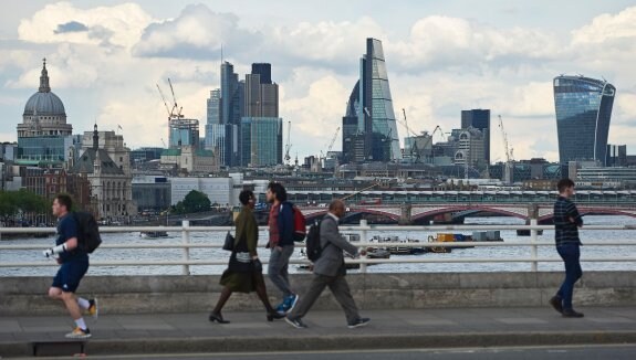 Peatones caminan por la ciudad de Londres con los edificios más emblemáticos de la City al fondo. :: afp