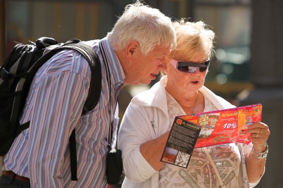 Turistas ingleses buscan en un plano turístico de la capital de Málaga. :: SUR