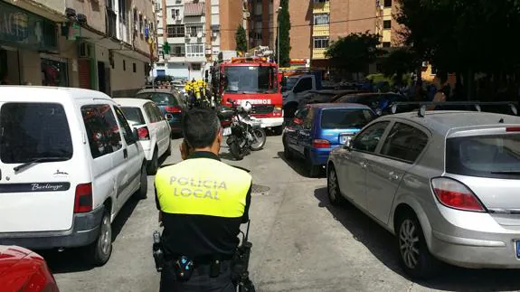 Un camión escala de Bomberos y efectivos de la Policía local ante el bloque en el que se ha declarado el incendio.