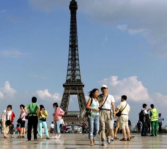 Turistas pasean por las inmediaciones de la Torre Eiffel. :: afp