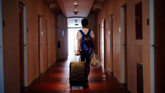Un joven recorre el pasillo de un hotel tras registrarse como cliente.