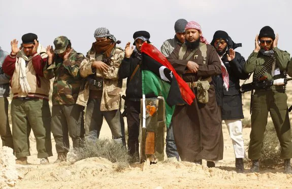 Milicianos de la insurgencia rezan junto a la tumba de diez compañeros fallecidos en un ataque aéreo de la coalición. :: reuters