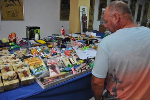 Un aficionado ojea un puesto lleno de juguetes antiguos y artículos de coleccionista. 