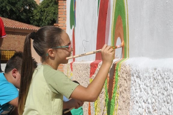 Luna Lázaro, alumna de sexto de Primaria, ayuda a pintar el mural de Carlos Casado, una portería multicolor.