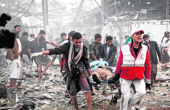 Personal sanitario y algunos voluntarios evacúan del lugar a los numerosos muertos y heridos causados por el bombardeo. :: AFP
