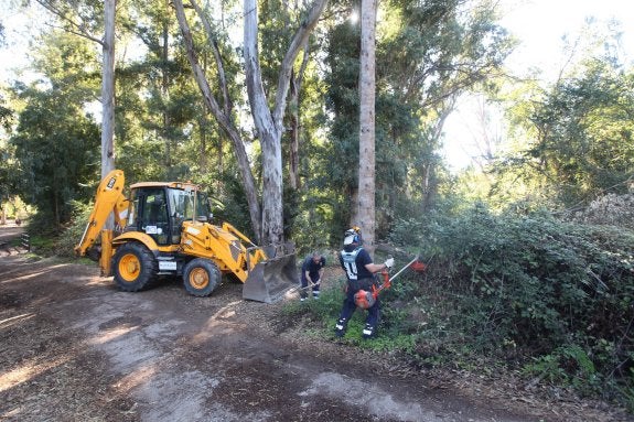 Trabajadores de la Renta Básica, junto a una máquina excavadora, ayer, durante los trabajos de desbroce y limpieza. 