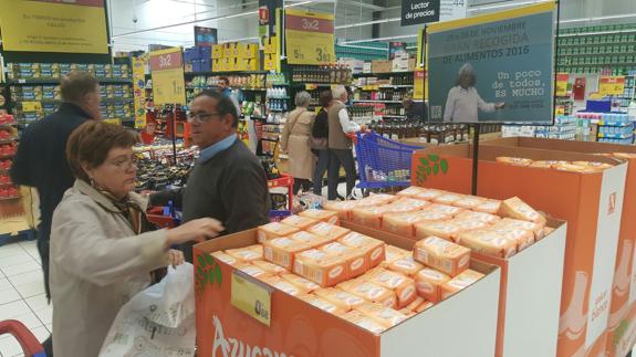 Varias personas llenan bolsas de la Gran Recogida en un establecimiento de Málaga.